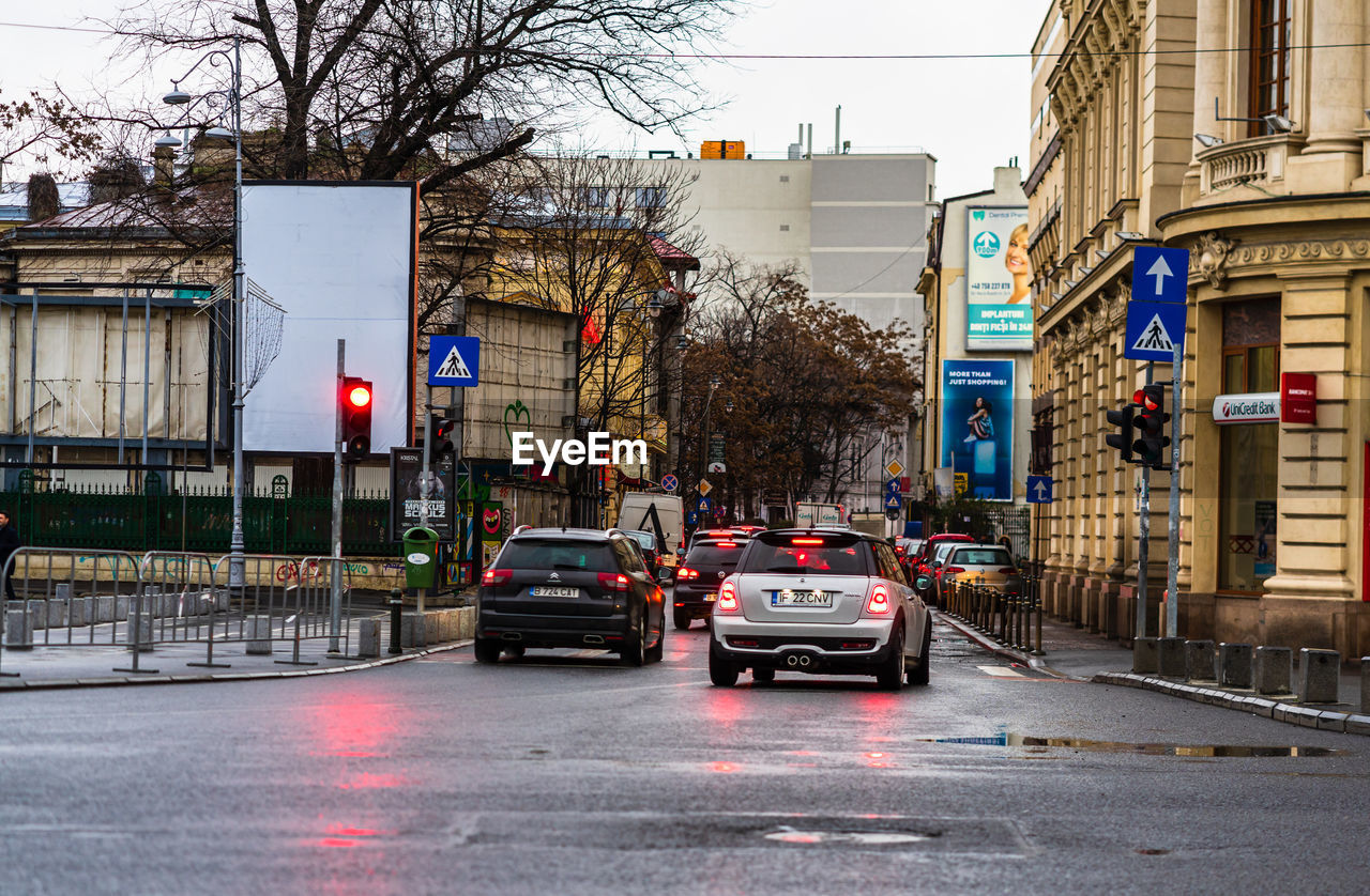 CARS ON STREET AGAINST BUILDINGS IN CITY