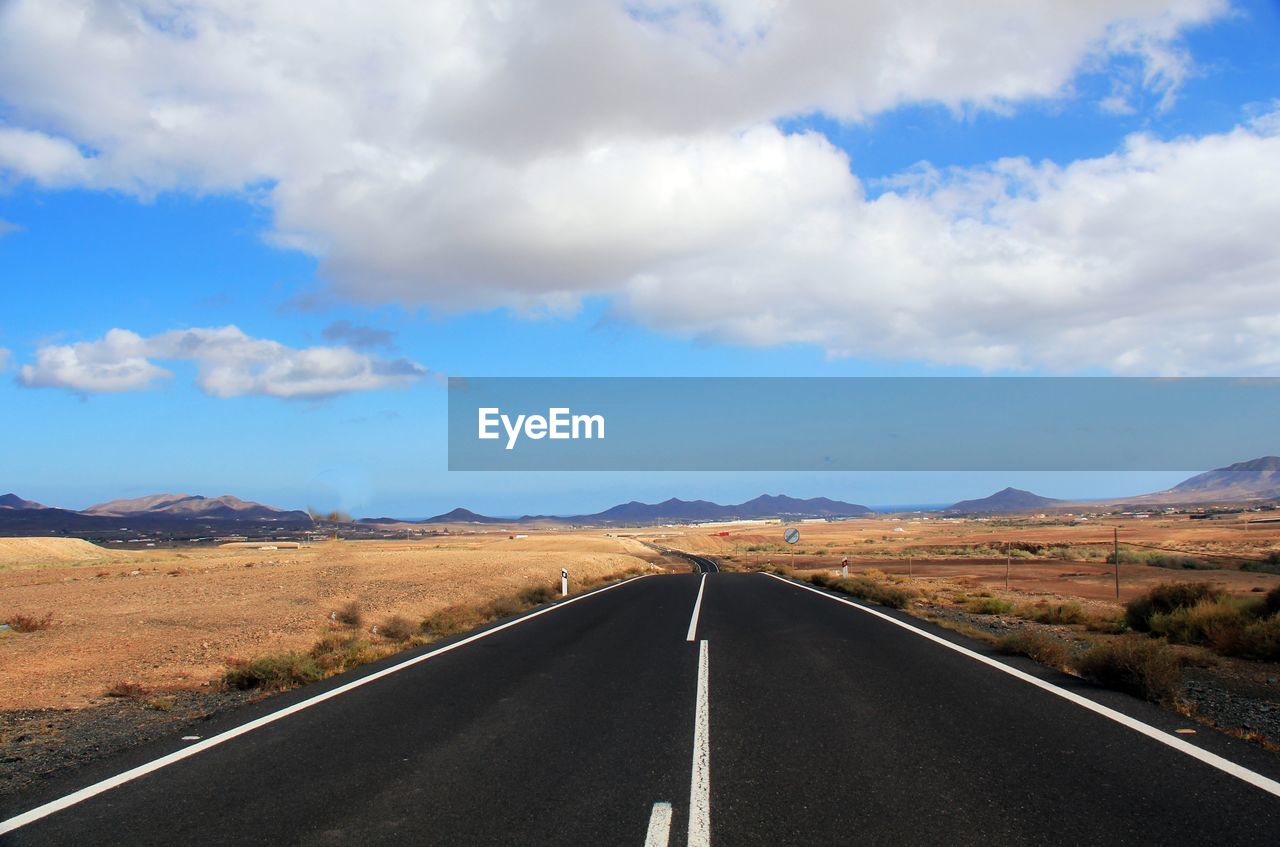 Empty road along landscape against sky