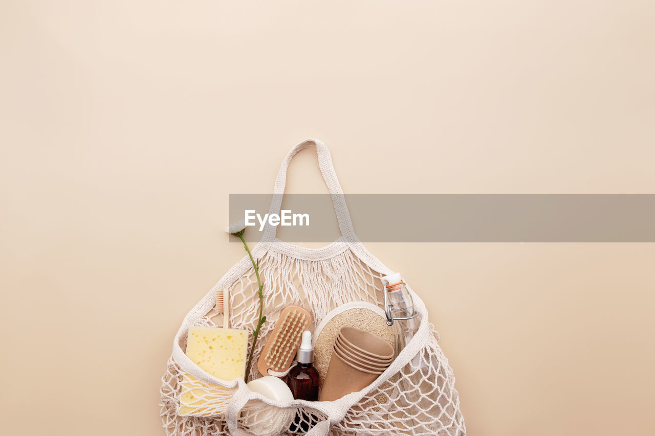 Beige background, eco friendly shopping bag, chamomile flowers, bath accessories, glass bottle, soap