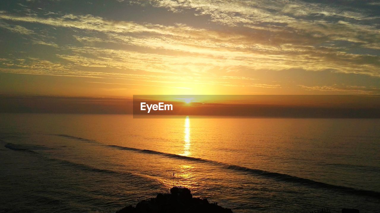 Scenic view of sea against dramatic sky during sunset