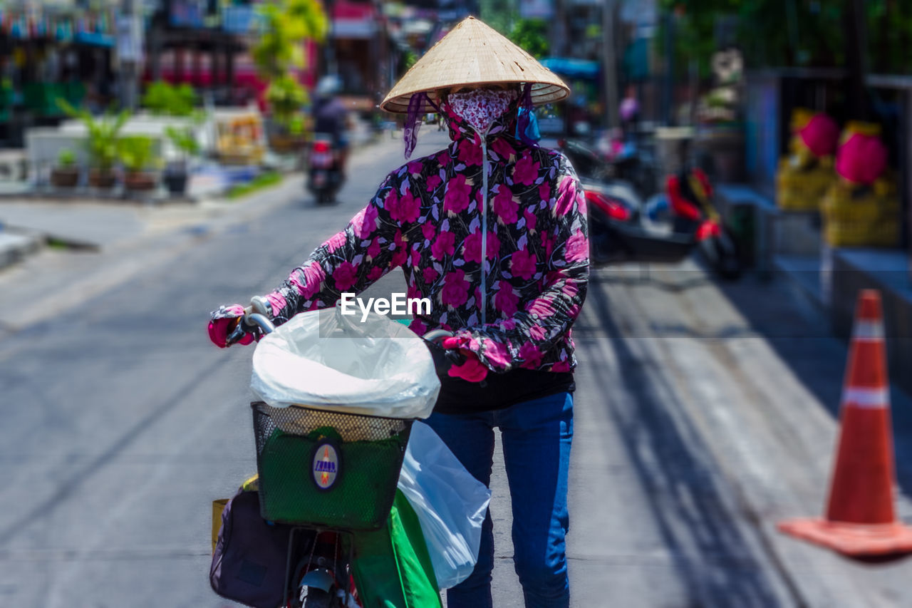 REAR VIEW OF WOMAN WITH UMBRELLA ON STREET