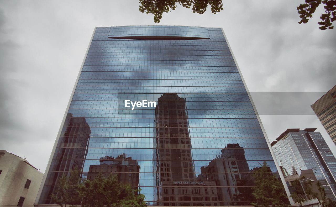 Low angle view of buildings reflection on glass in city