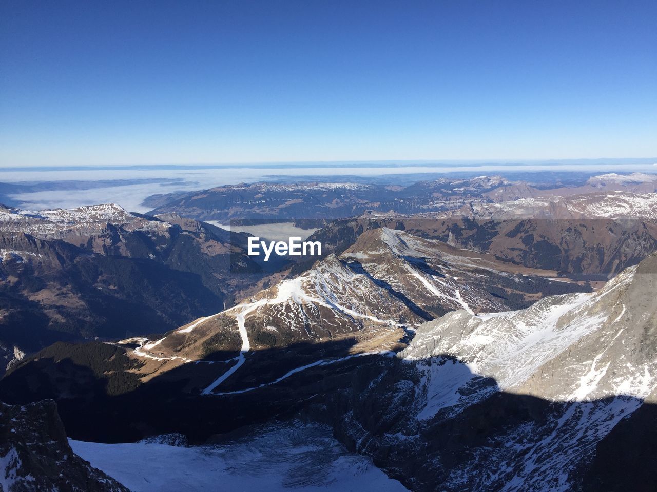Aerial view of snowcapped mountains against clear blue sky