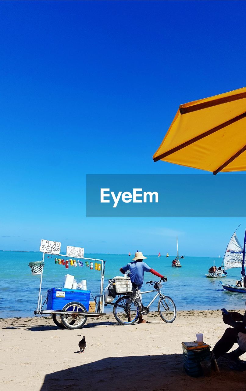 BICYCLES ON BEACH AGAINST CLEAR SKY