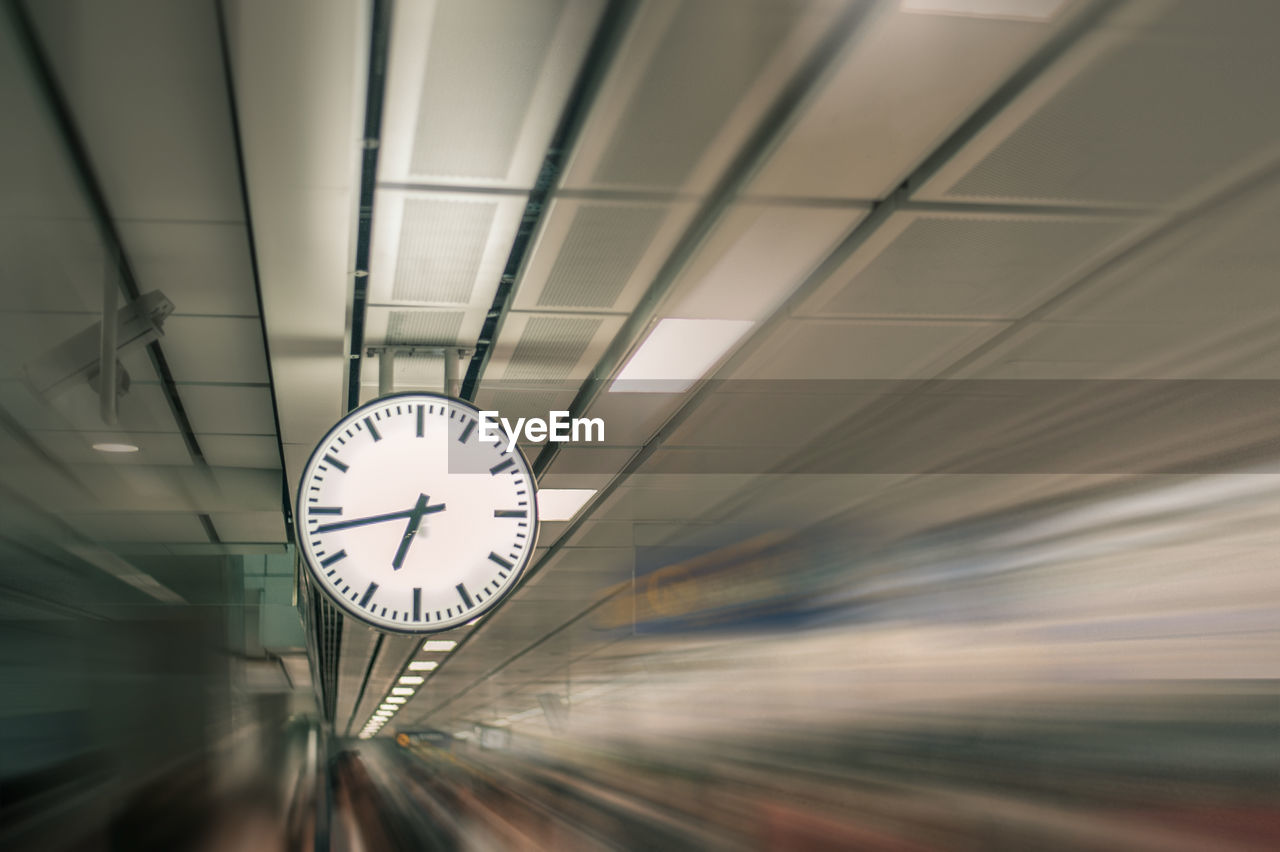 LOW ANGLE VIEW OF ILLUMINATED CLOCK ON CEILING AT NIGHT