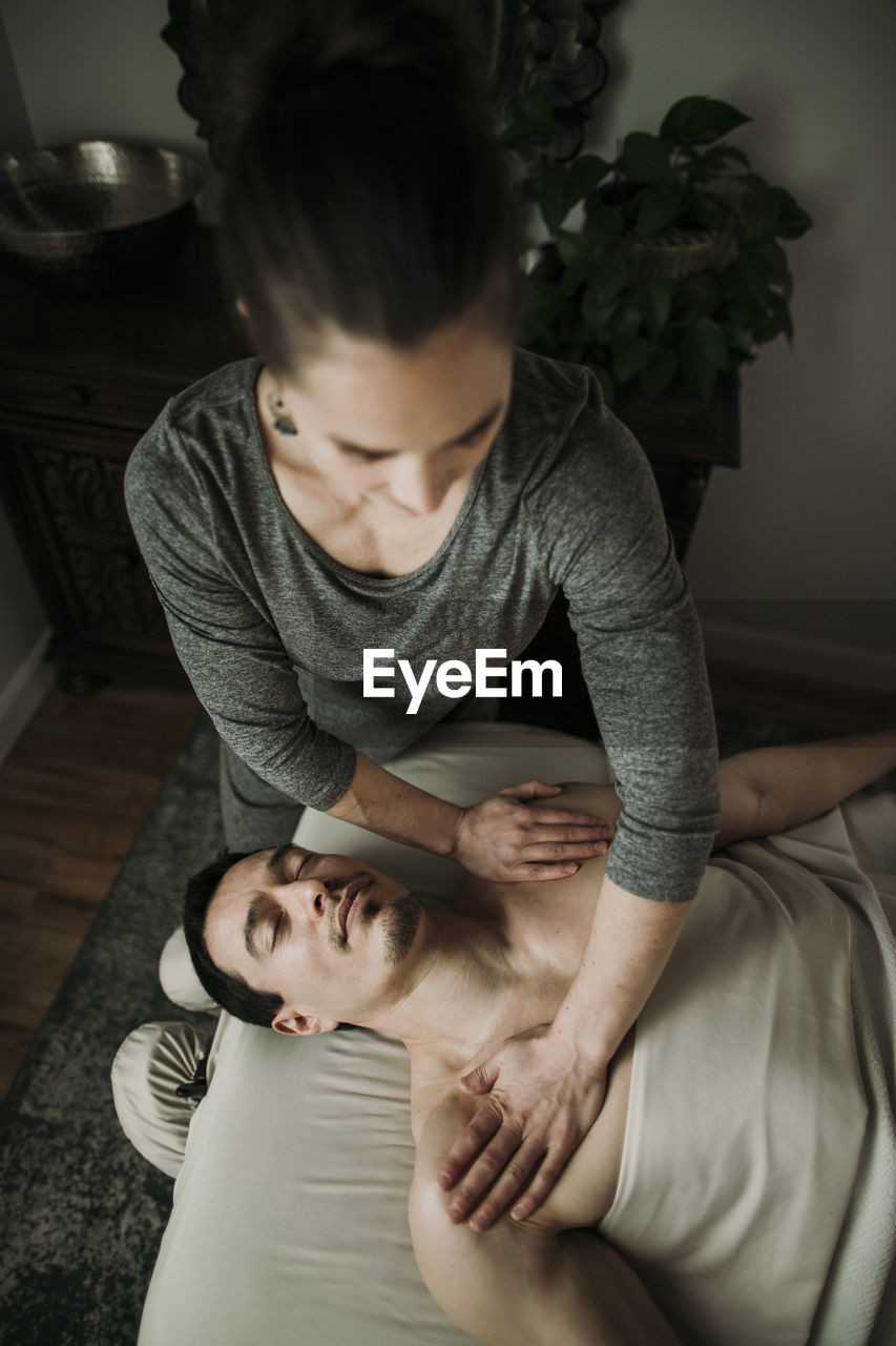Male massage client receives pressure on his shoulders from therapist