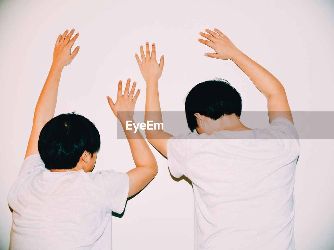 Rear view of boys leaning on white wall