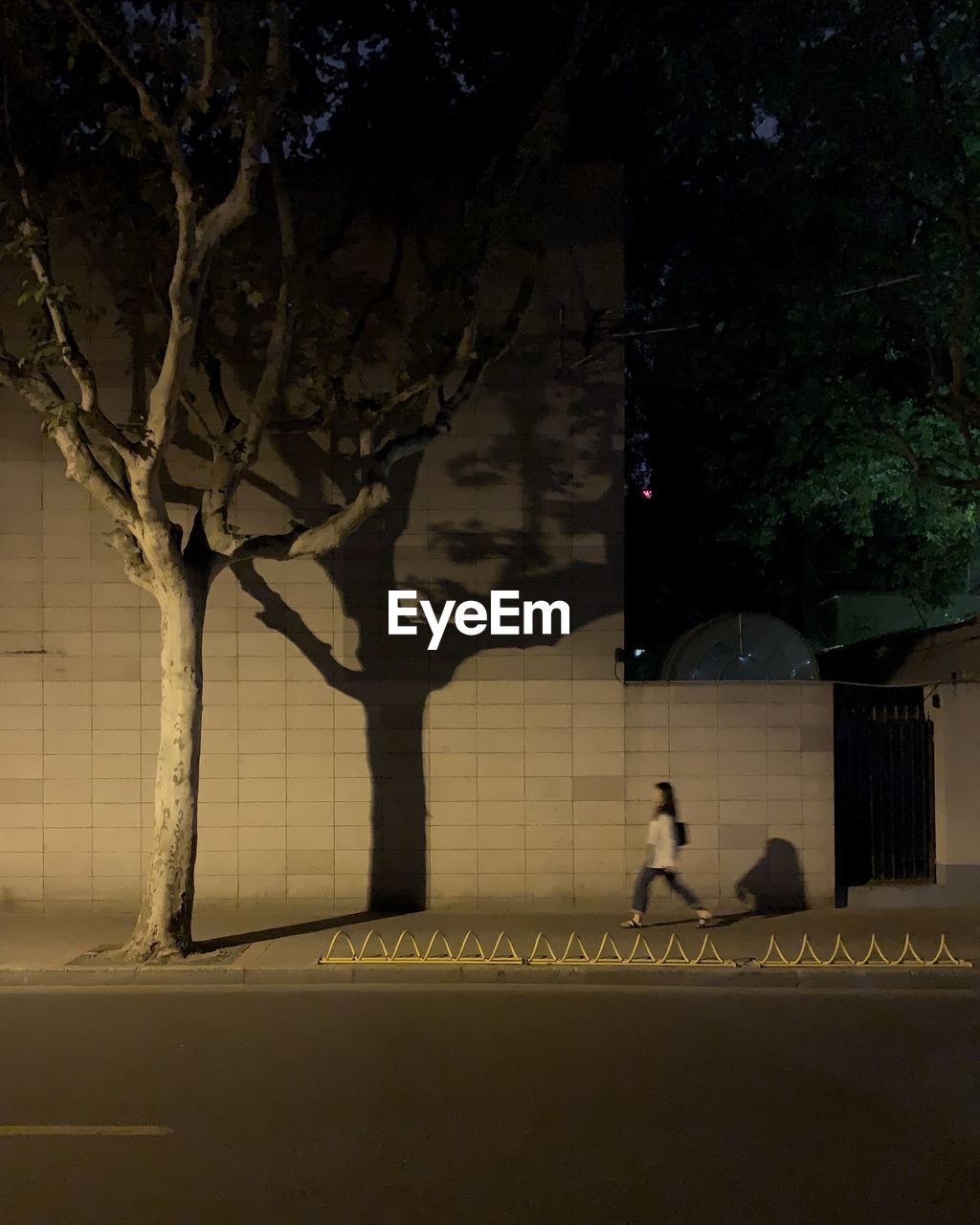 Blurred motion of woman walking on sidewalk at night