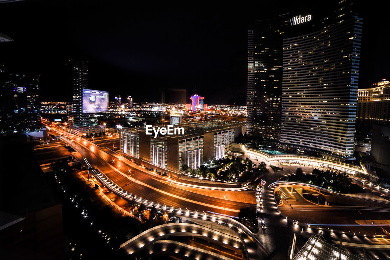 HIGH ANGLE VIEW OF ILLUMINATED STREET AMIDST BUILDINGS IN CITY AT NIGHT