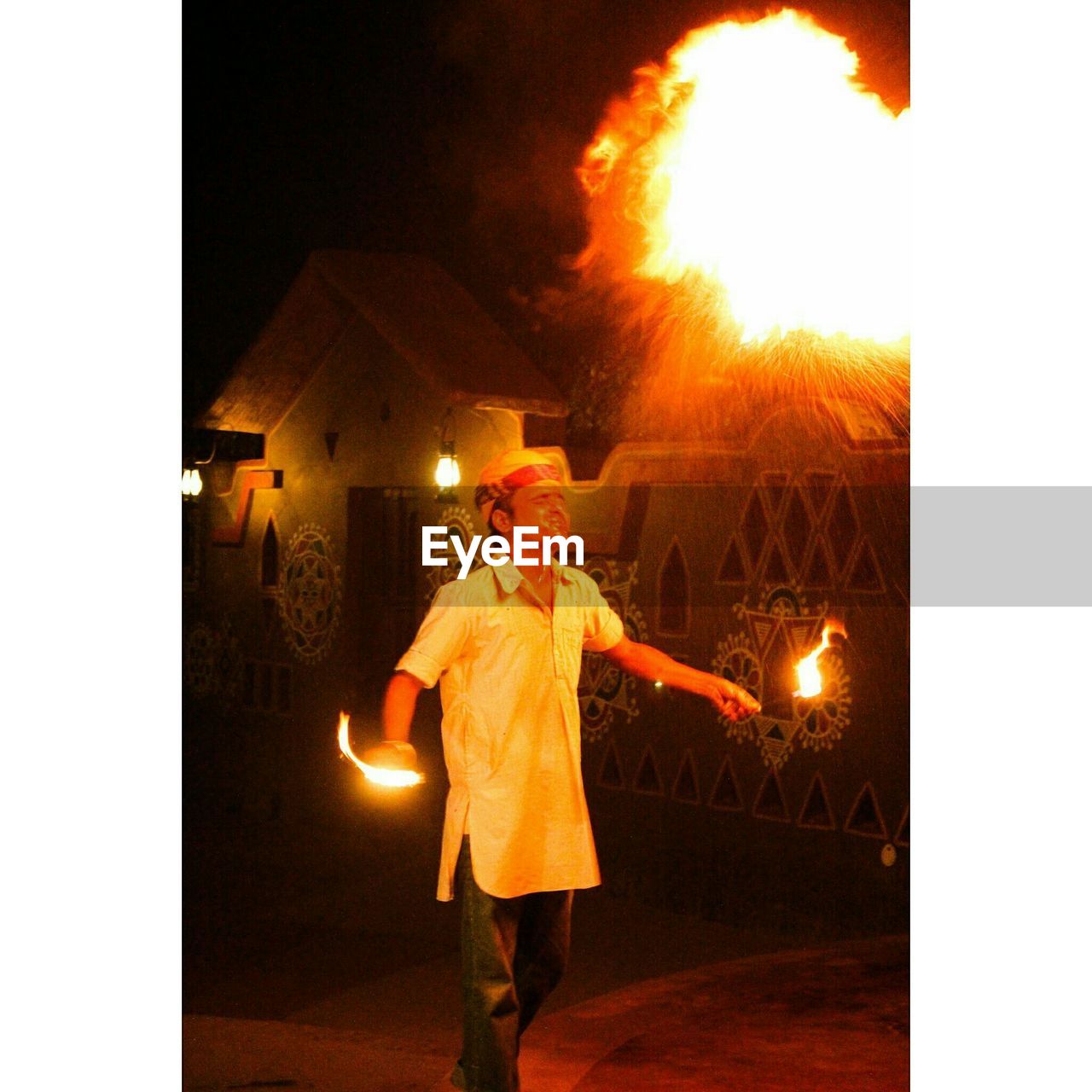Fire-eater blowing fire in village at night