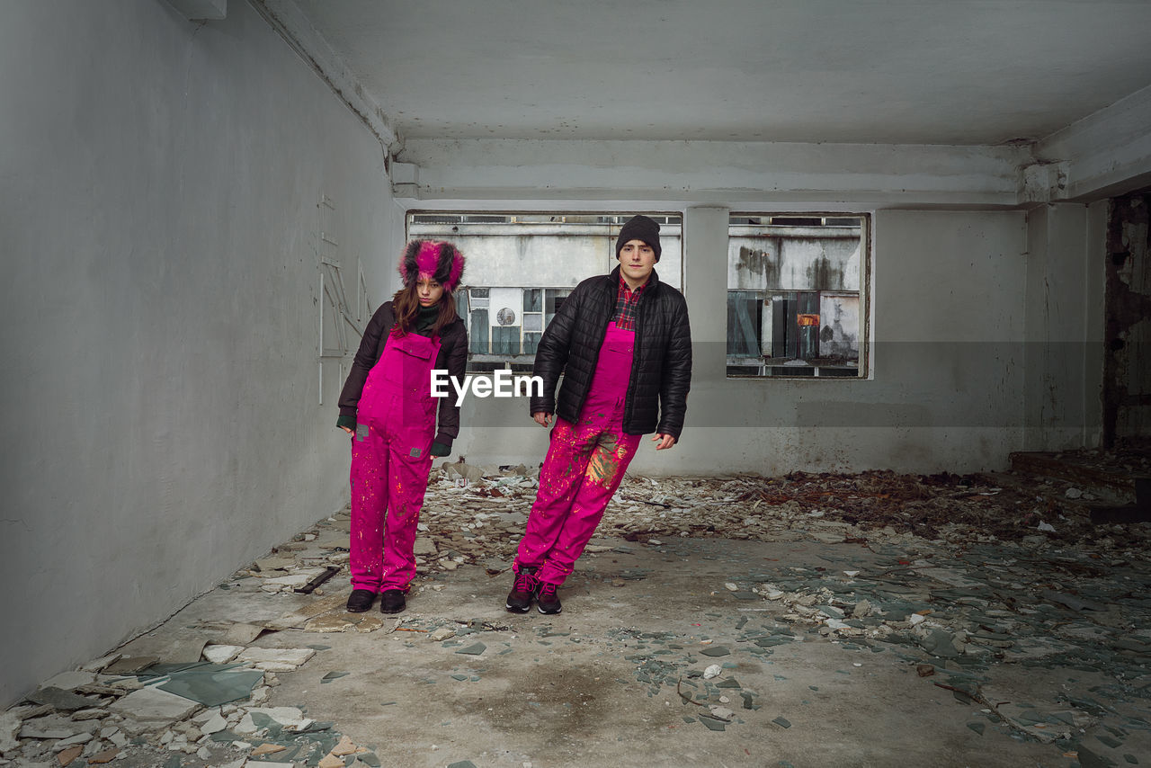 Portrait of couple wearing warm clothing while standing in abandoned house