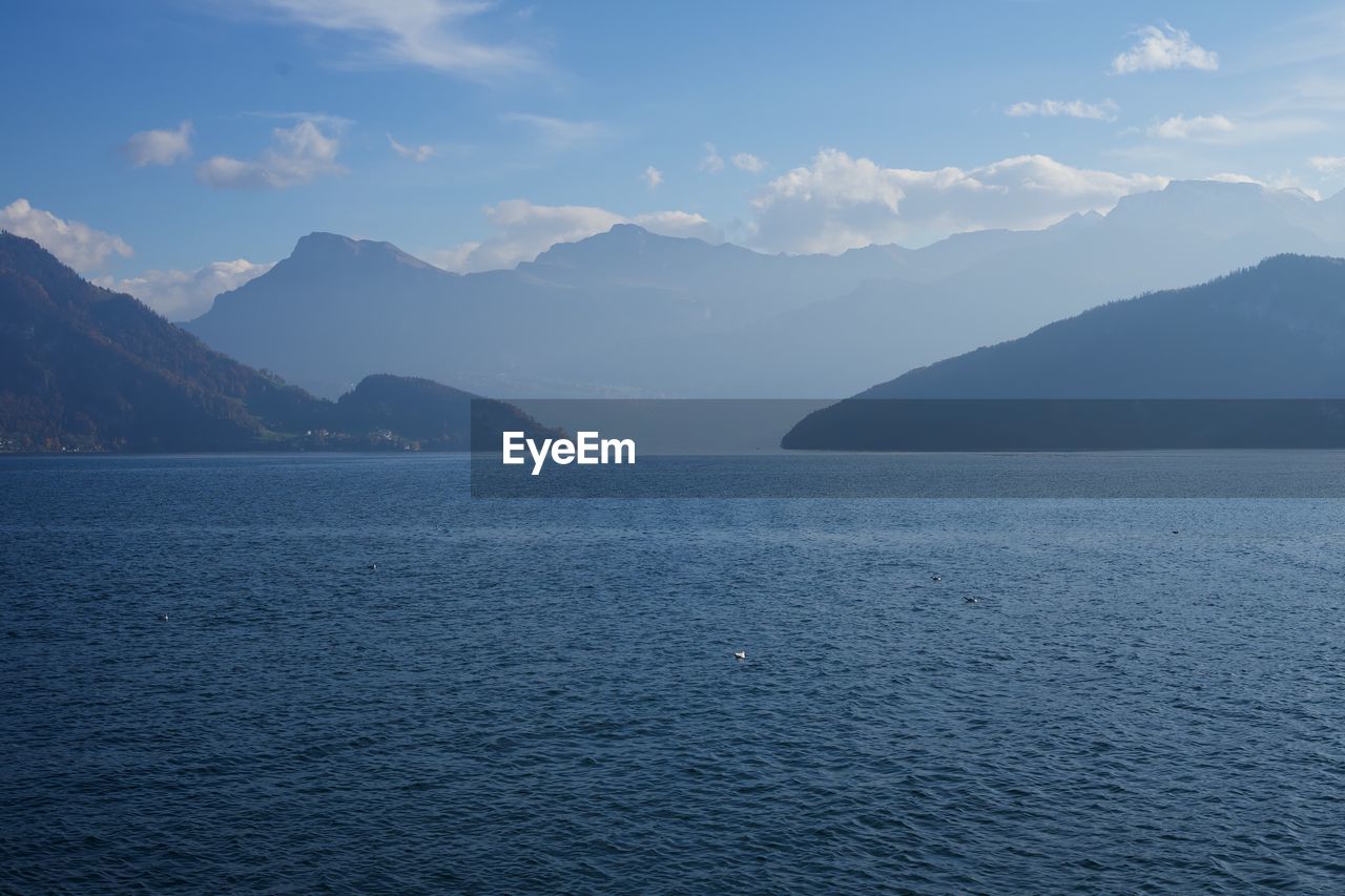 Scenic view of sea by mountains against sky