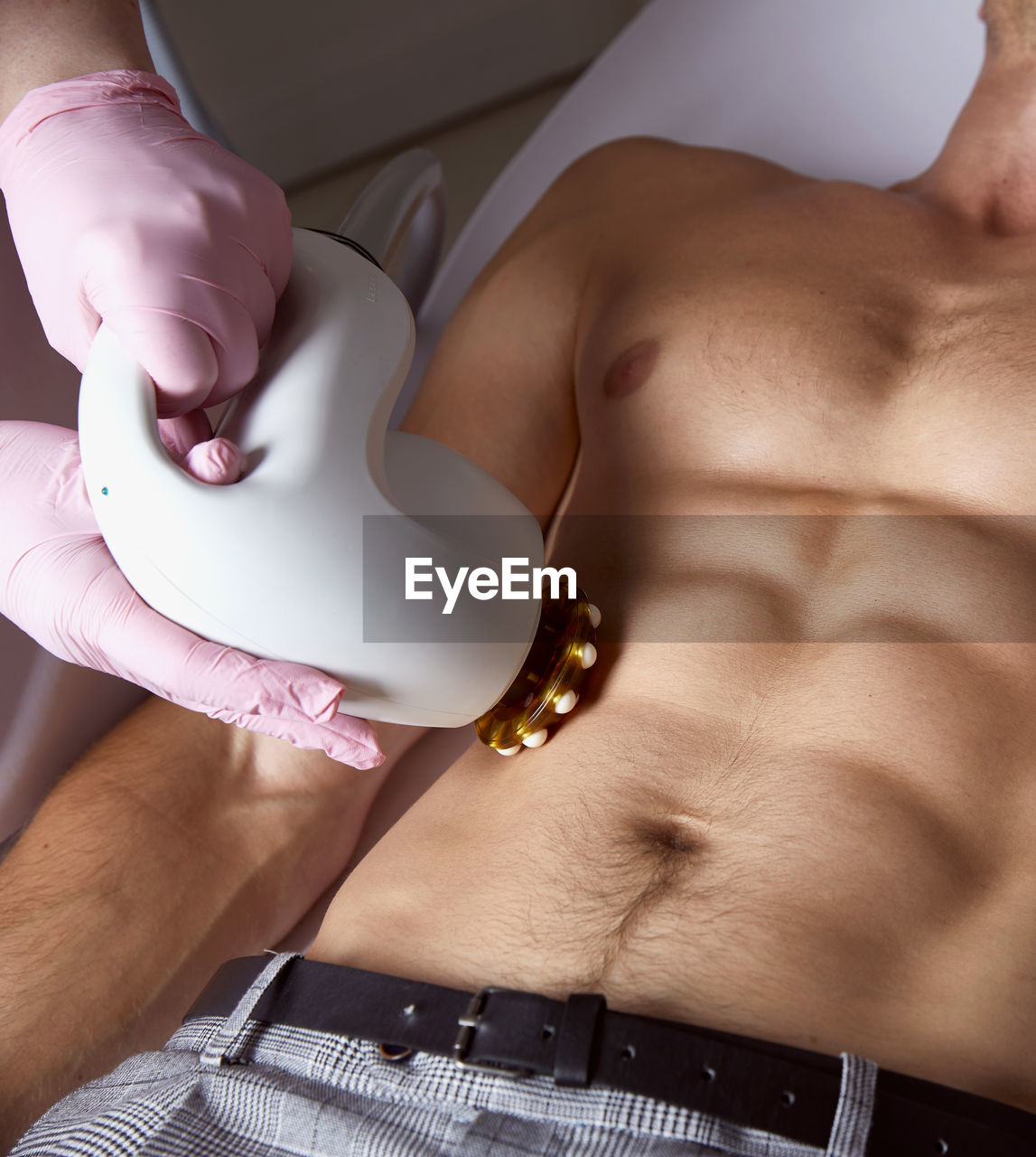 Man receiving fat reductive skin lifting body treatment on modern equipment at cosmetology clinic