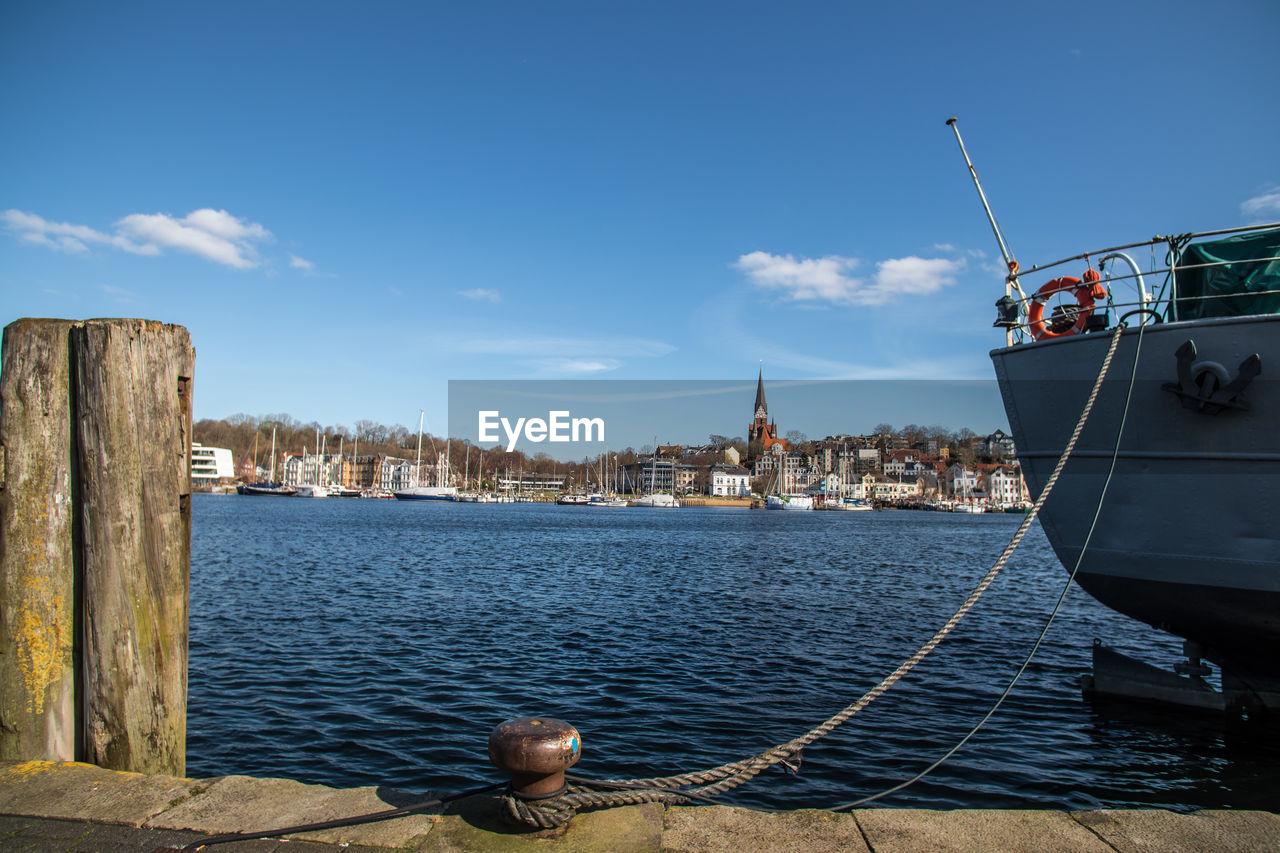 SAILBOATS MOORED IN HARBOR AGAINST SKY