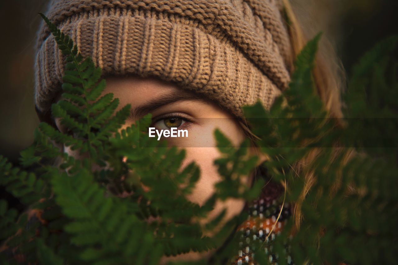 Close-up portrait of teenage girl wearing knit hat by plants