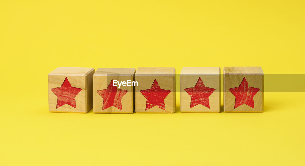 Five wooden cubes with a red star on a yellow background. quality assessment concept, rating. 