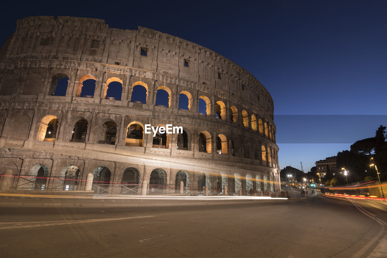 Low angle view of coliseum against sky at night