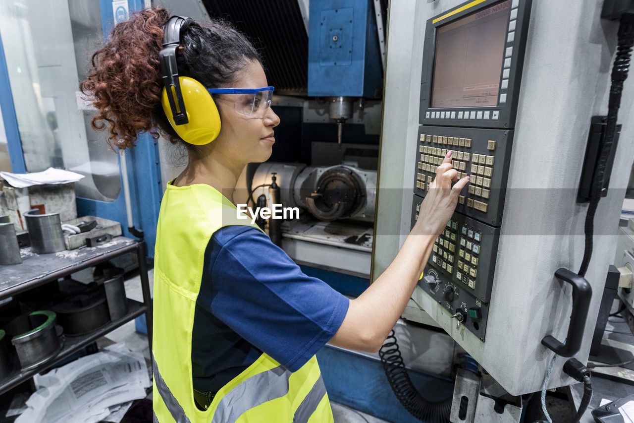 Engineer in protective workwear operating cnc machine in modern factory