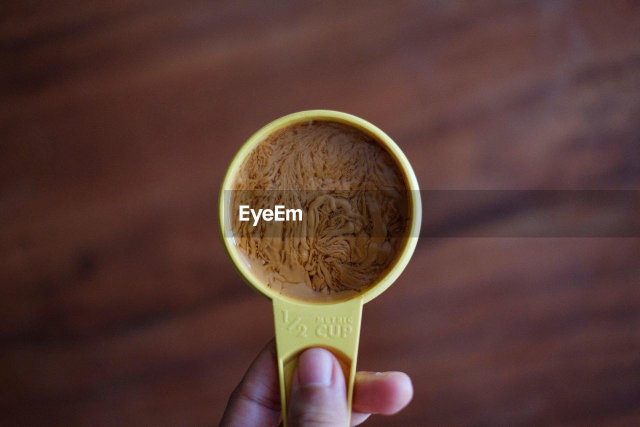 Person holding peanut butter in measuring cup