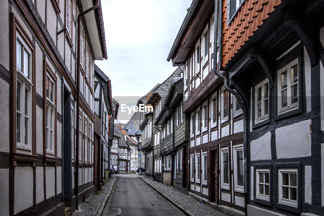 Empty street amidst old houses in town against sky