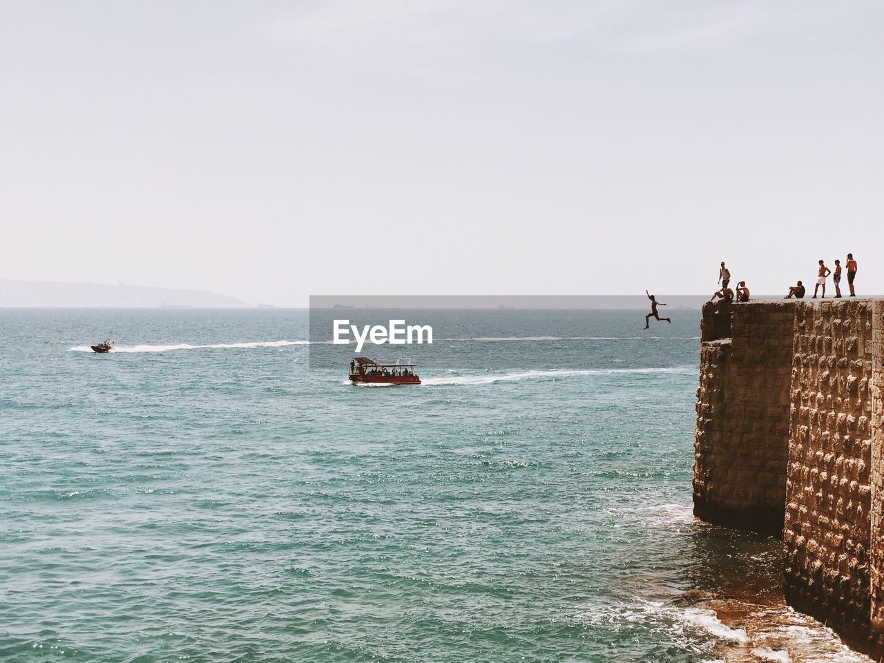 People on seaside against clear sky