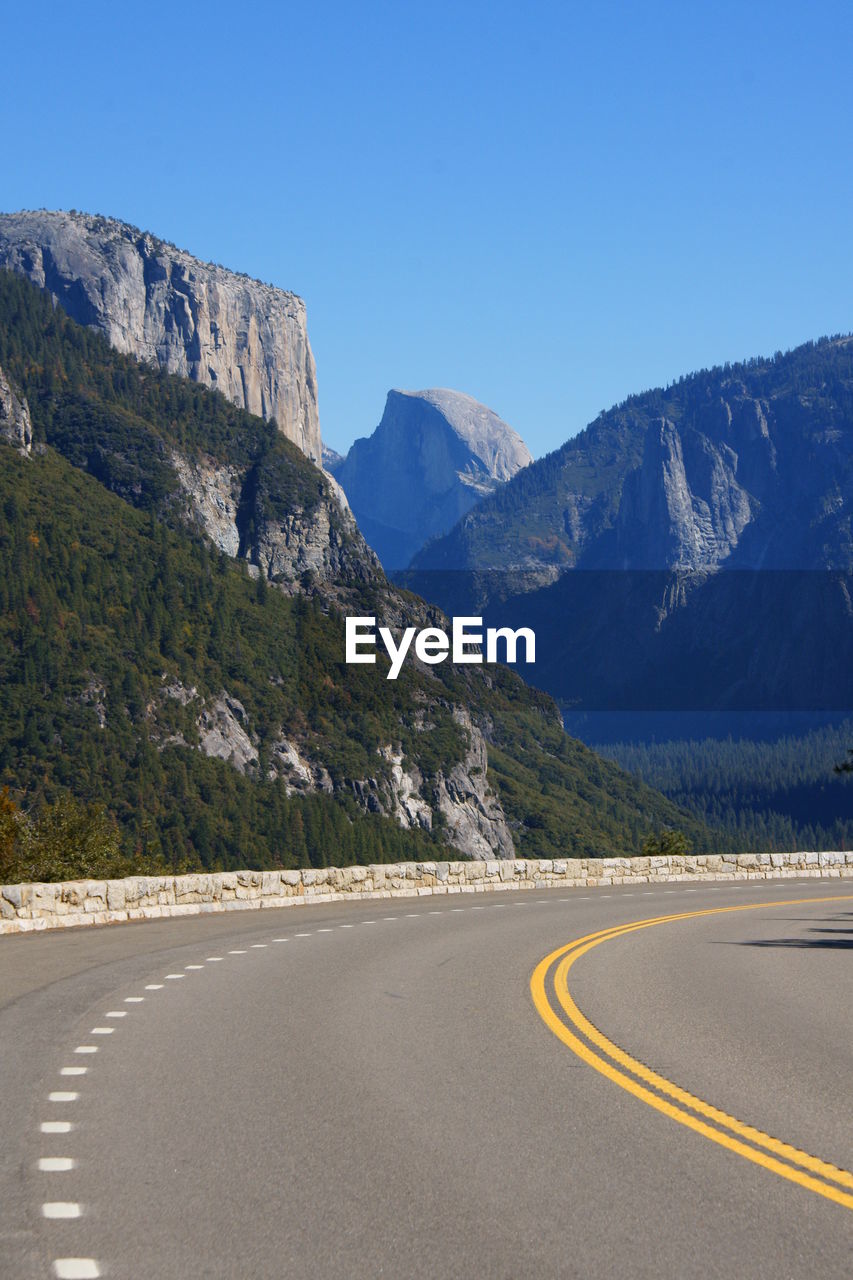 ROAD LEADING TOWARDS MOUNTAINS AGAINST CLEAR BLUE SKY