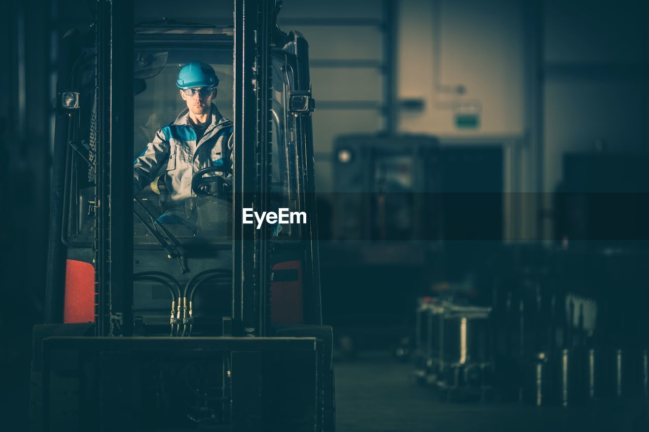 Worker riding forklift in factory