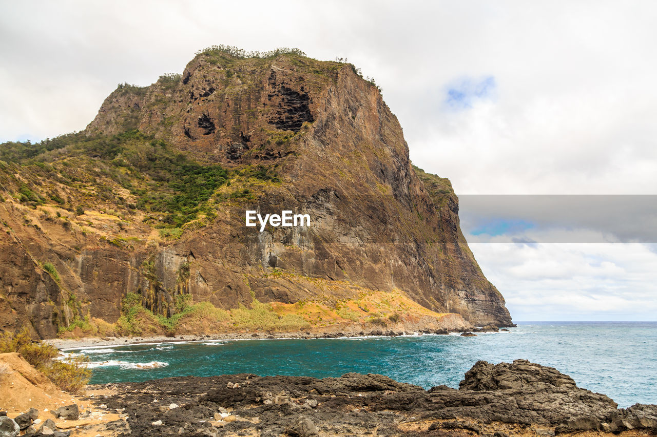 Rock formation by sea against sky