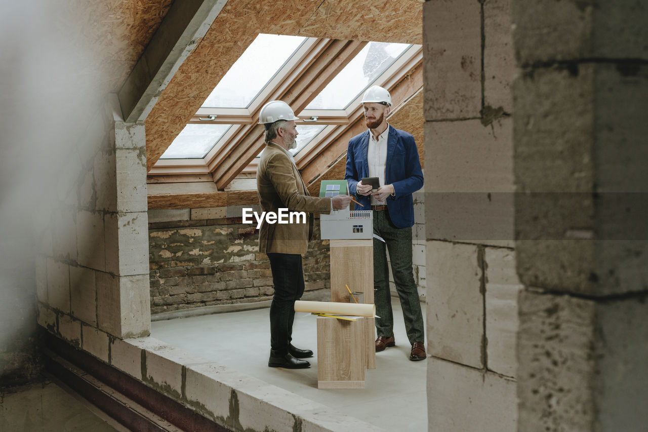 Architects discussing by house model at construction site
