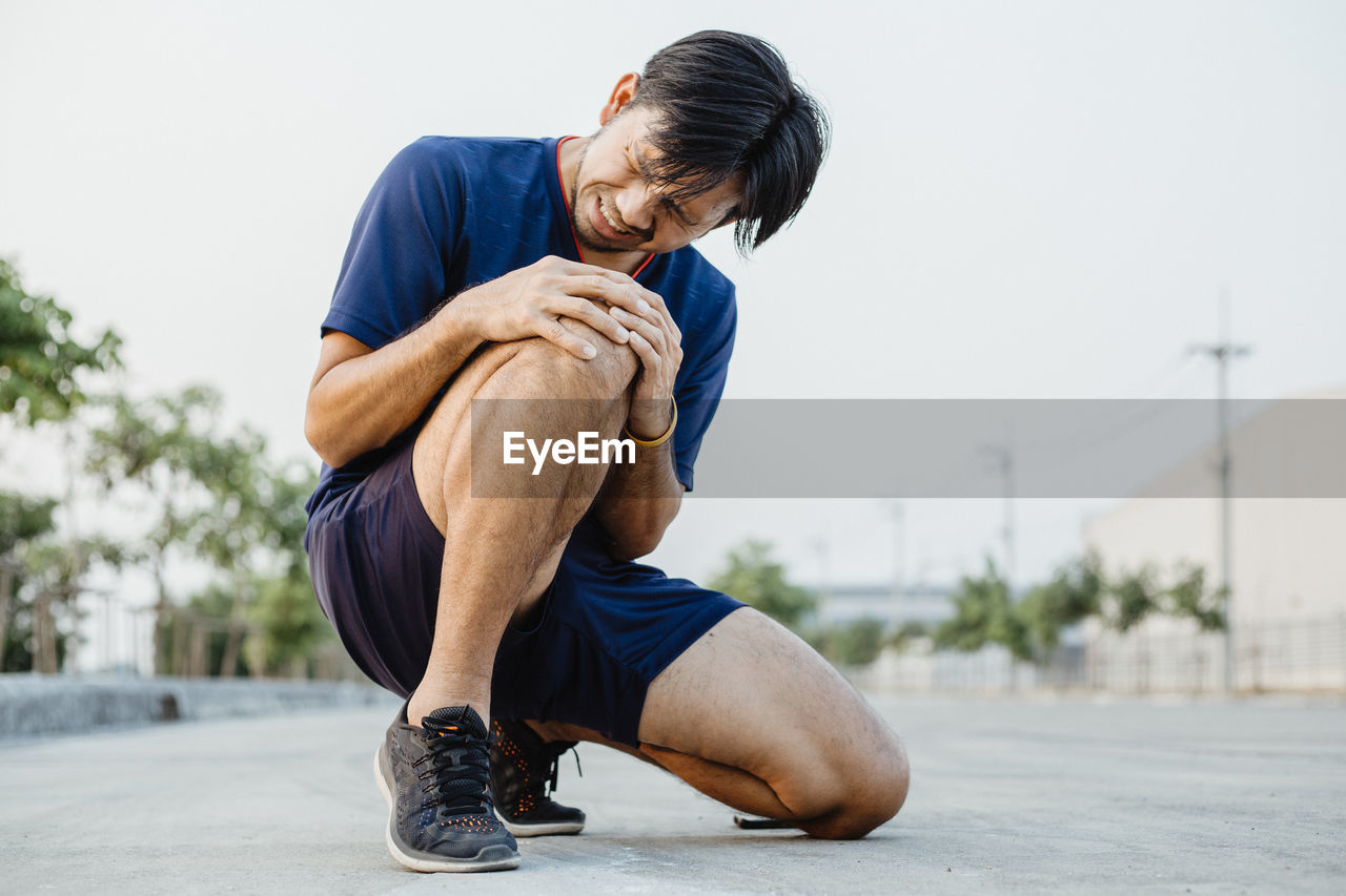 YOUNG MAN LOOKING AWAY WHILE SITTING ON CITY