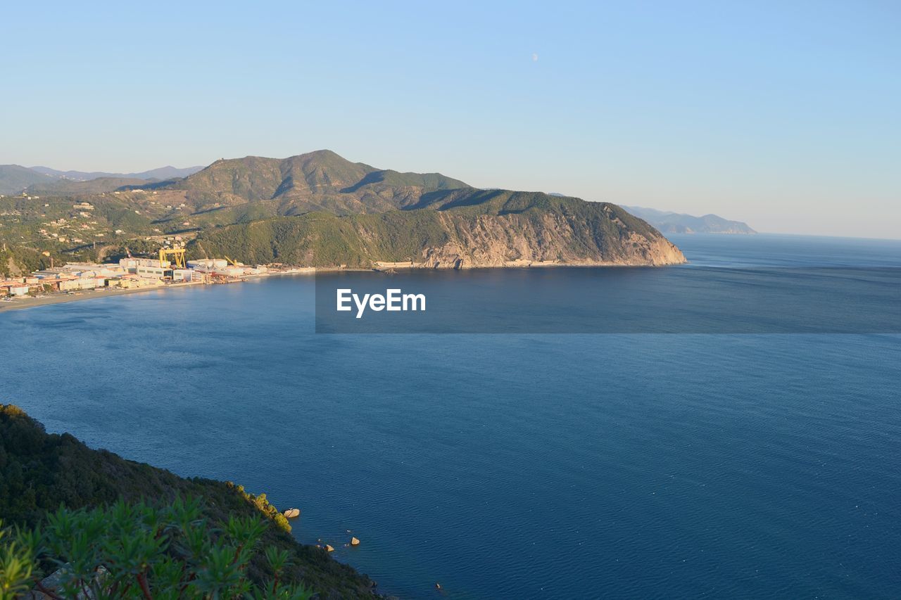 Scenic view of sea and mountains against clear blue sky