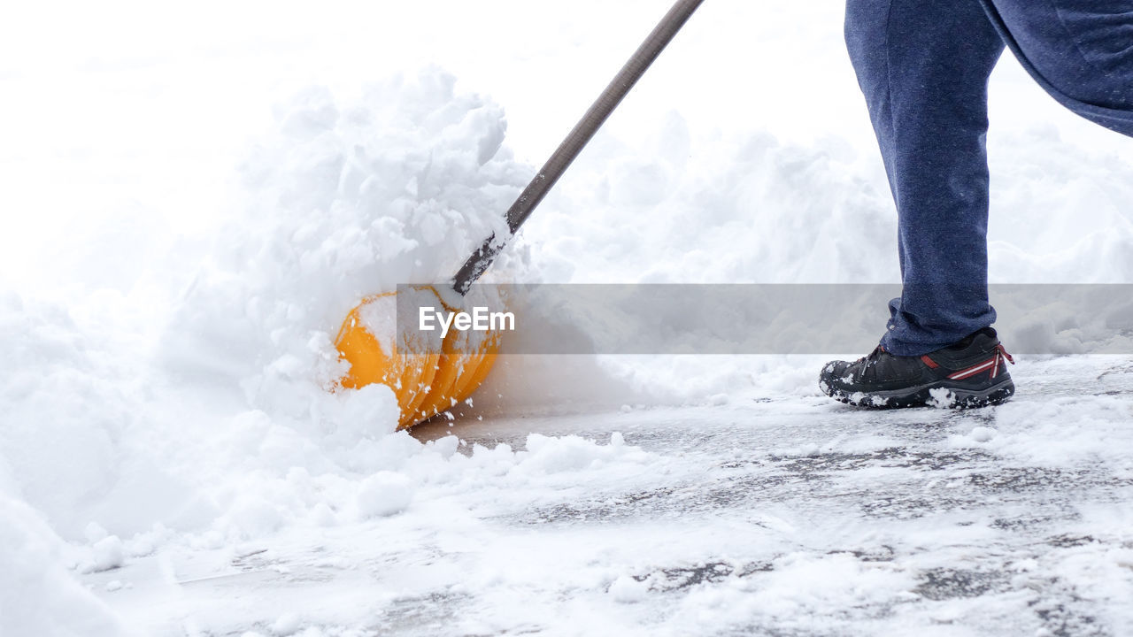 Man shoveling snow off of driveway in heavy snow storm 