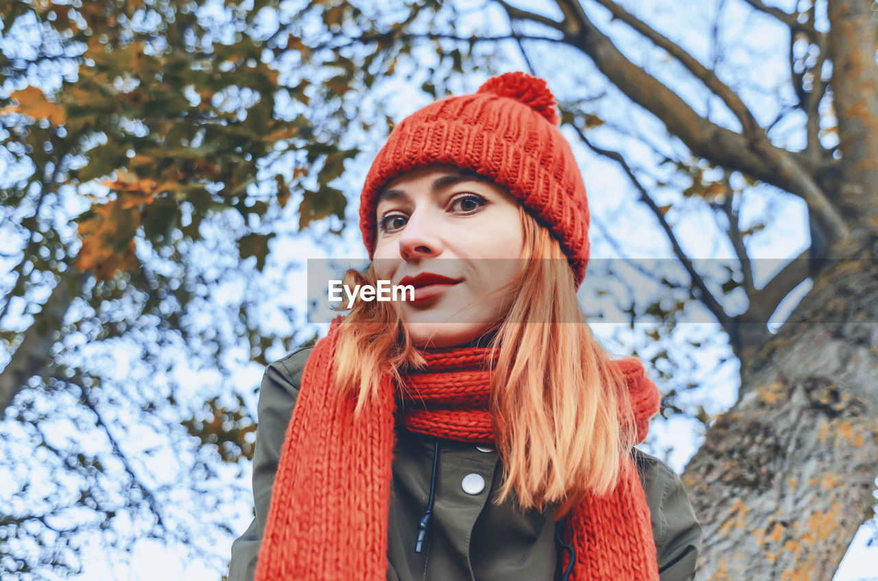 Autumn fashion portrait of stylish woman in bright orange knitted hat and scarf. playful look.