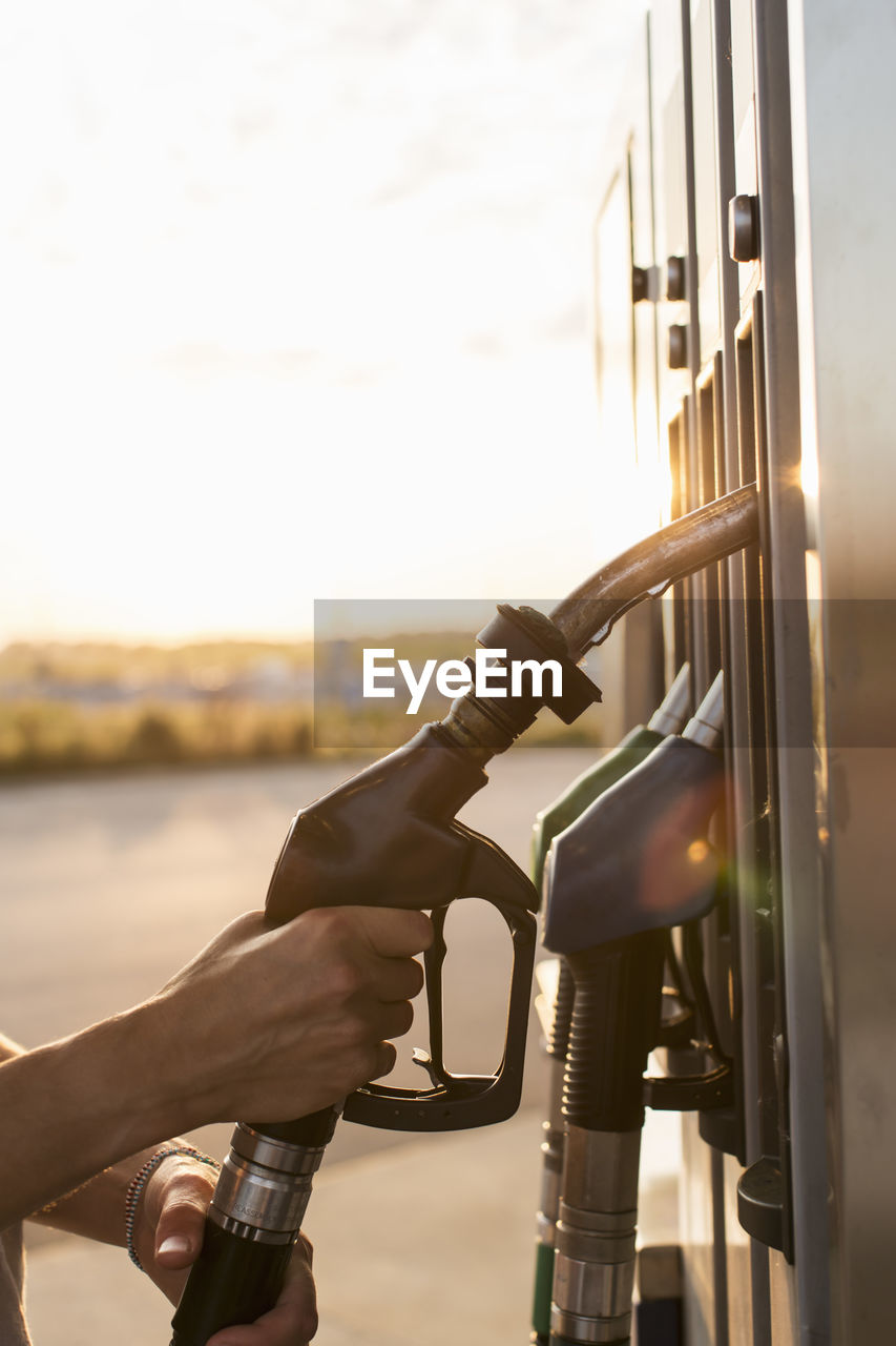 Cropped image of hand holding fuel pump at gas station