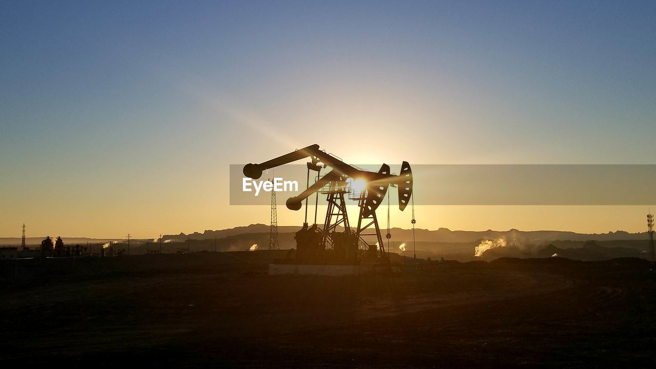 Silhouette crane on field against clear sky during sunset