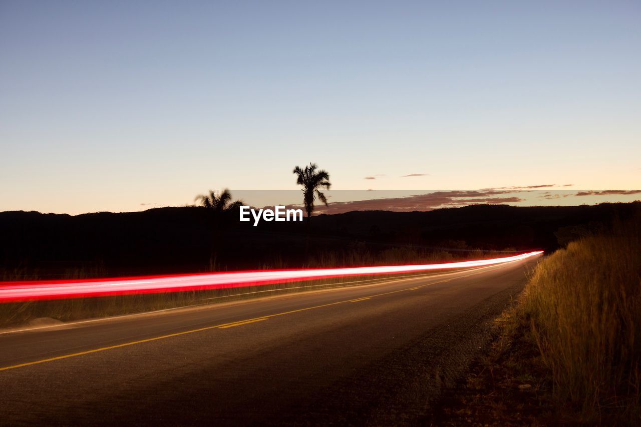 Light trails on road against clear sky at night