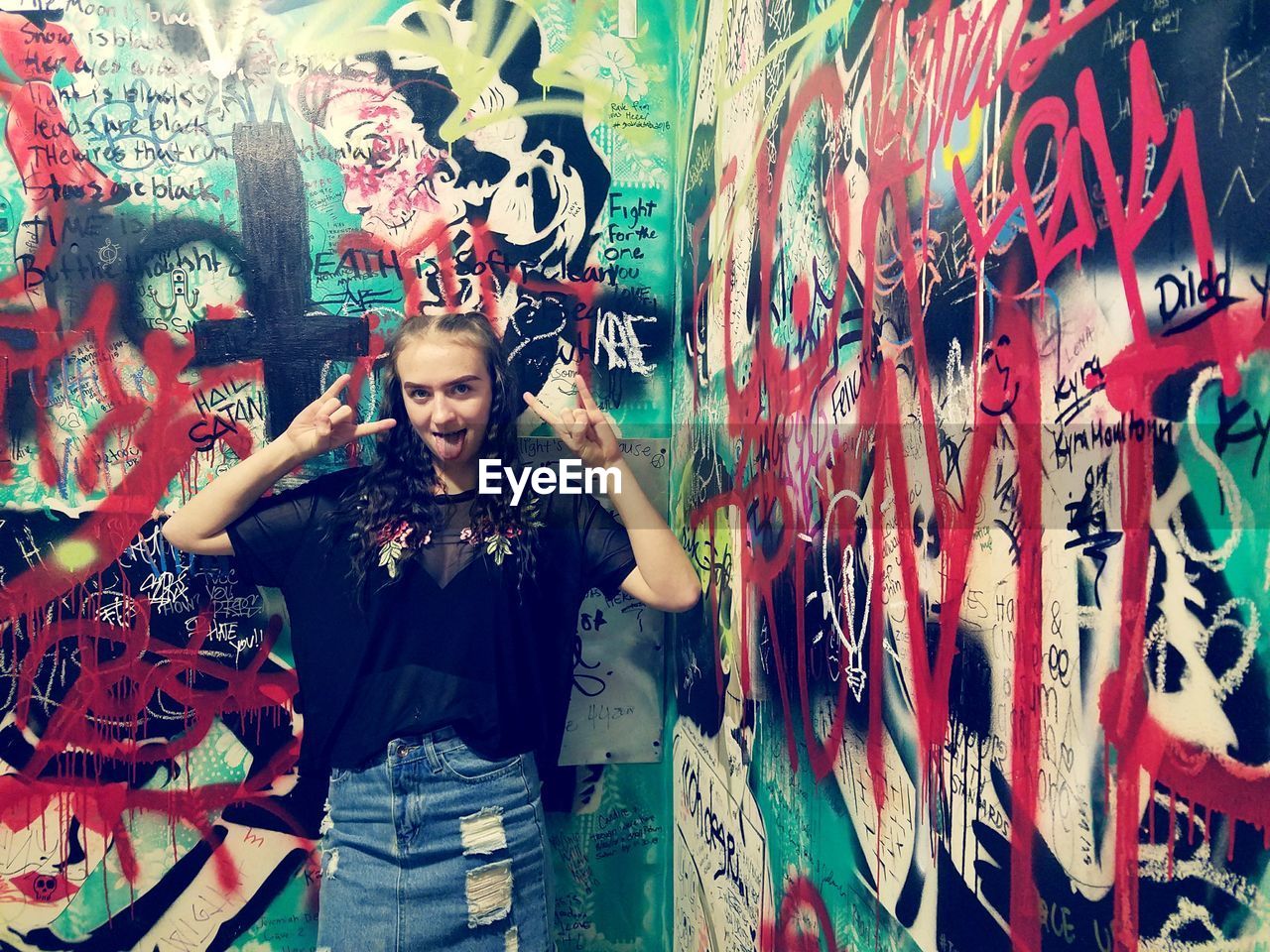 FULL LENGTH PORTRAIT OF YOUNG MAN STANDING AGAINST GRAFFITI WALL