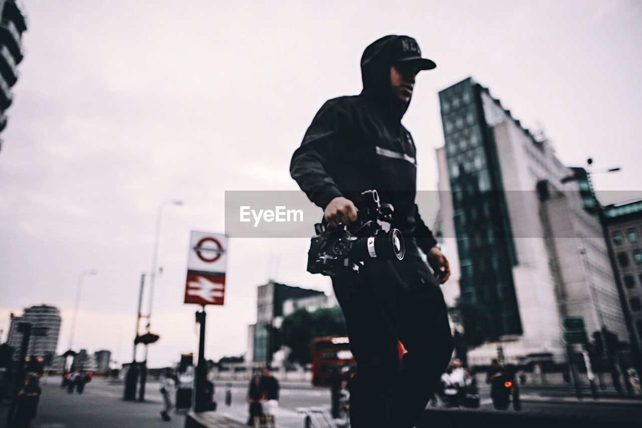 LOW ANGLE VIEW OF MAN STANDING ON STREET