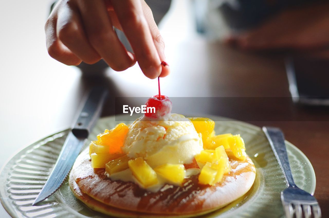 Cropped hand of person decorating dessert