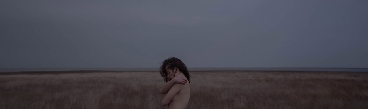 REAR VIEW OF WOMAN STANDING ON FIELD