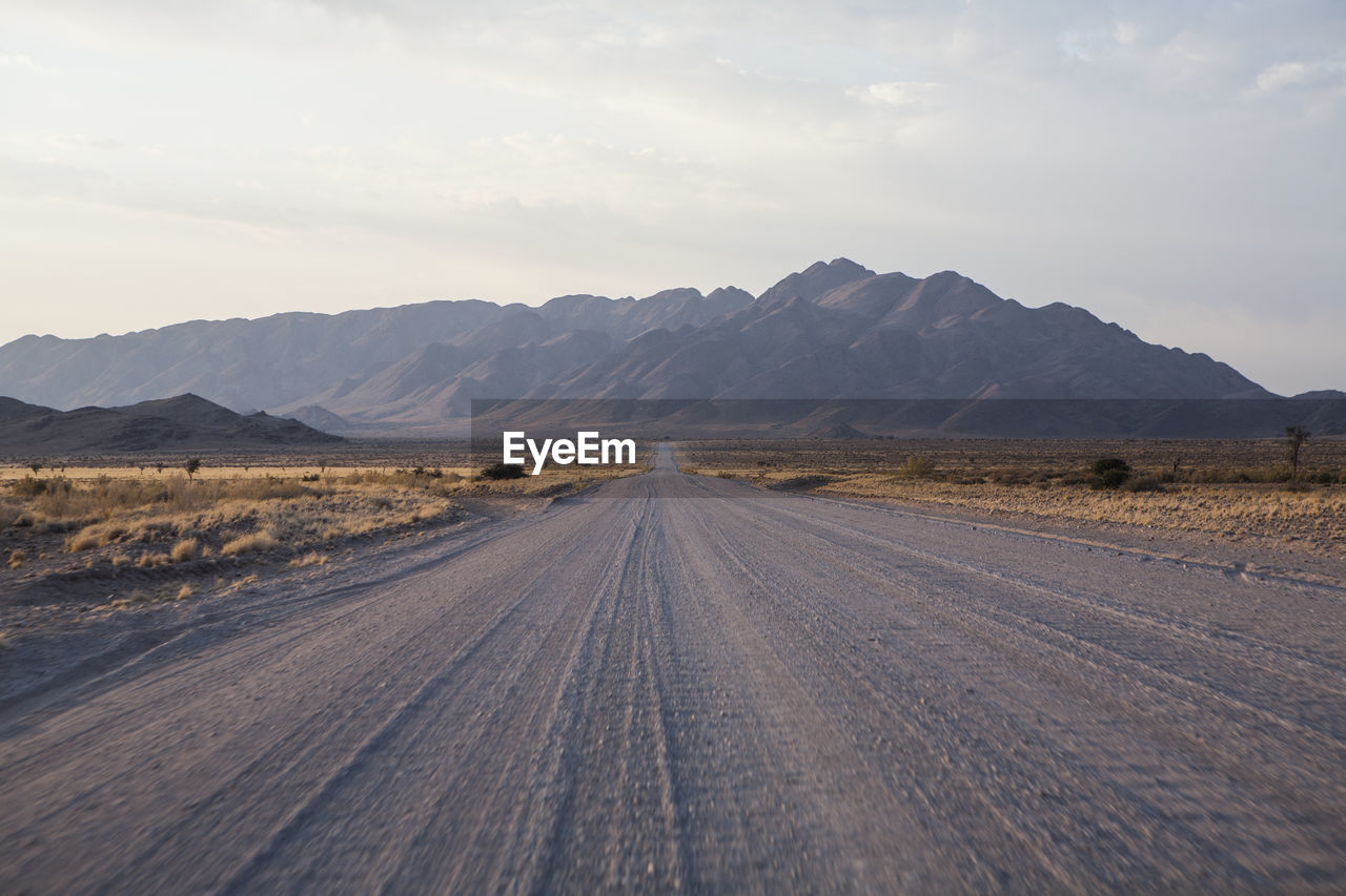 Road by desert against sky