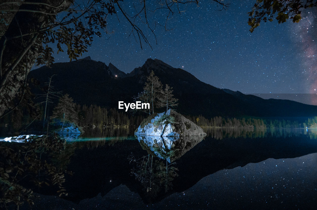 Reflection of tree in lake against sky at night