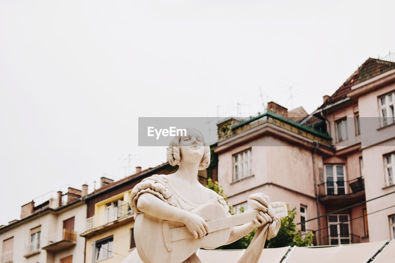 Low angle view of statue against building against clear sky