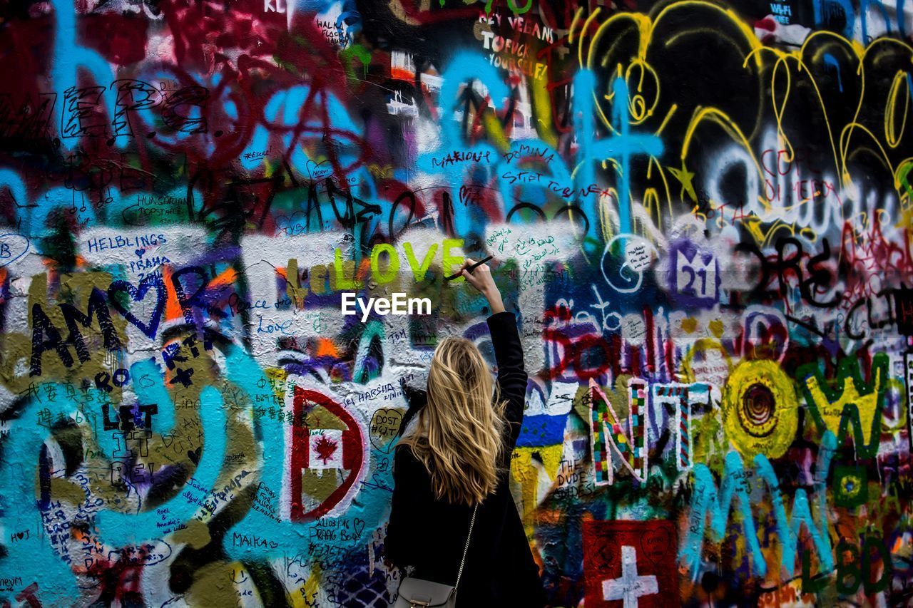 Rear view of woman painting on john lennon wall