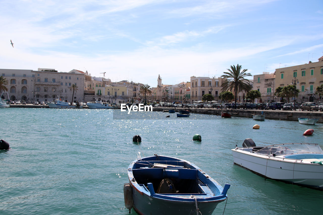 Boats in sea by city against sky