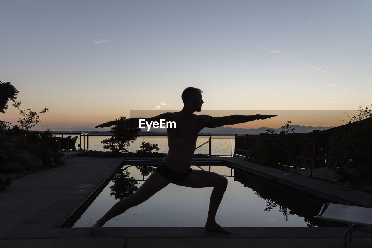 Man doing yoga during sunset