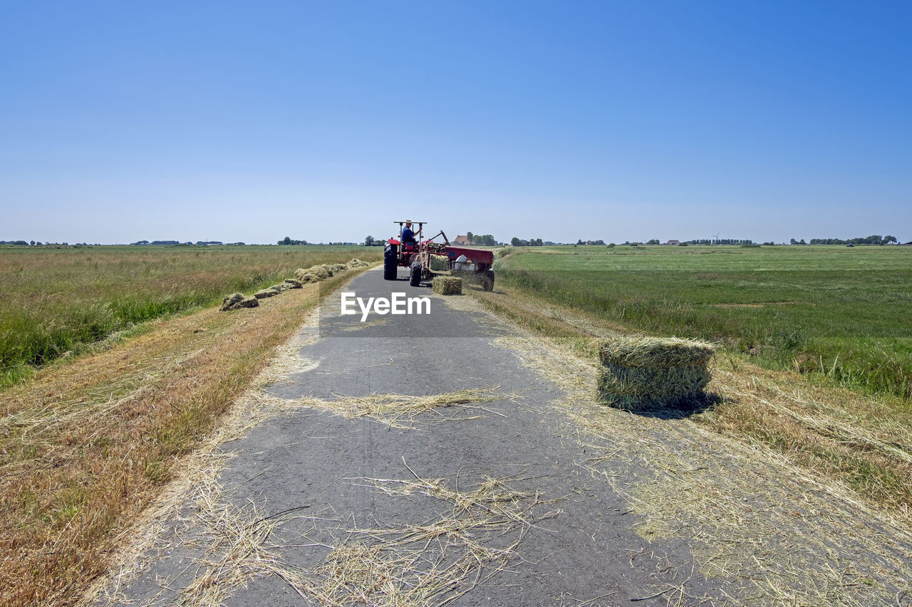 transportation, landscape, sky, road, environment, nature, rural scene, rural area, land, field, clear sky, prairie, plant, mode of transportation, blue, agriculture, day, travel, adult, hill, group of people, sunny, dirt, dirt road, the way forward, farm, soil, land vehicle, scenics - nature, motion, plain, outdoors, grass, men, vehicle, on the move, grassland, sunlight, copy space, diminishing perspective, non-urban scene, steppe, horizon, beauty in nature, journey