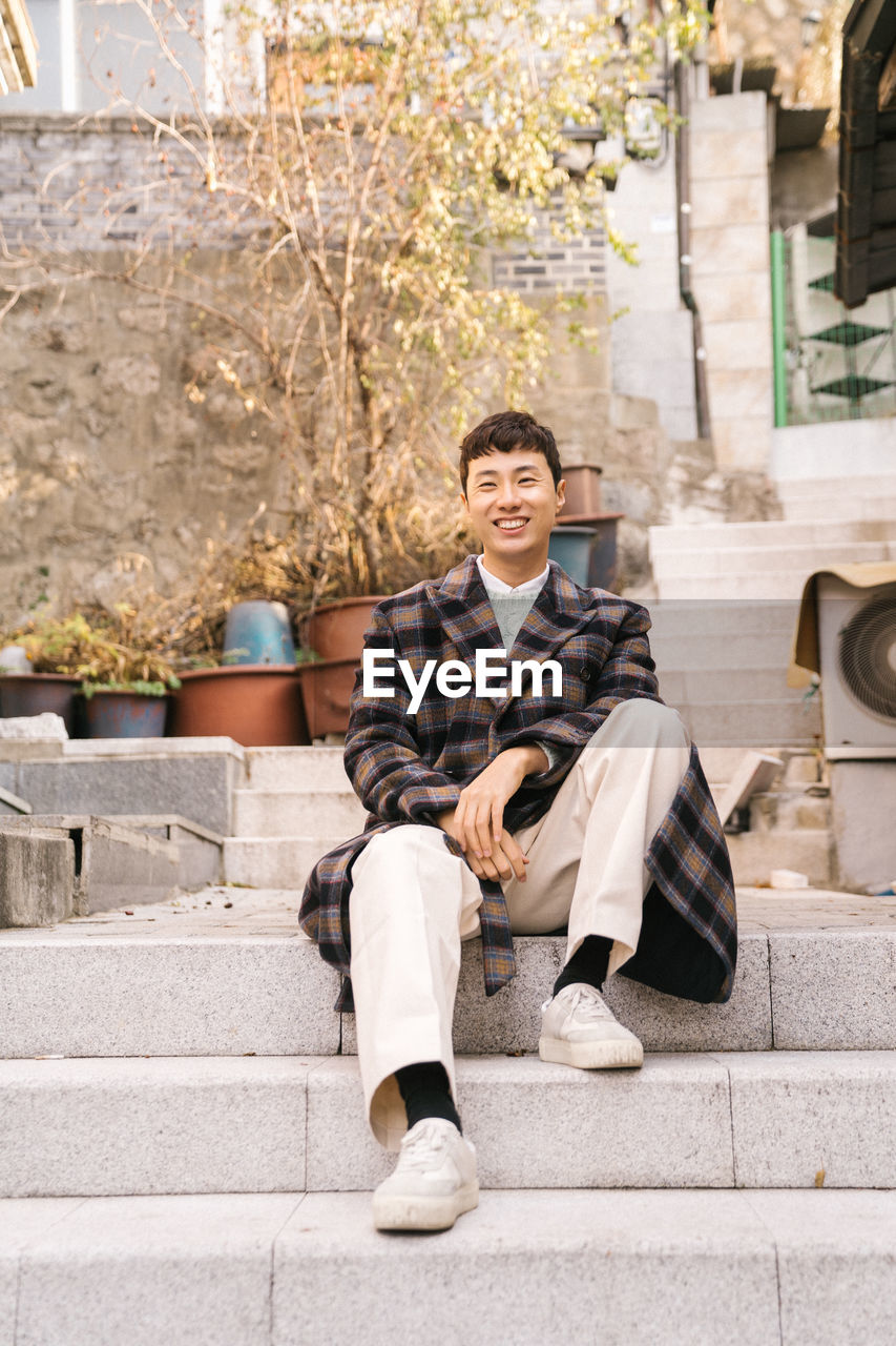 Portrait of young man sitting on staircase in city