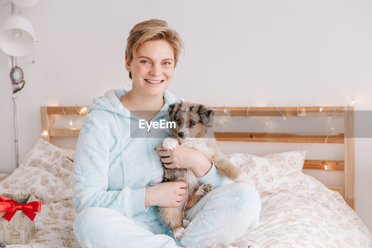 Young happy smiling caucasian woman with cute puppy dog pet at home. 