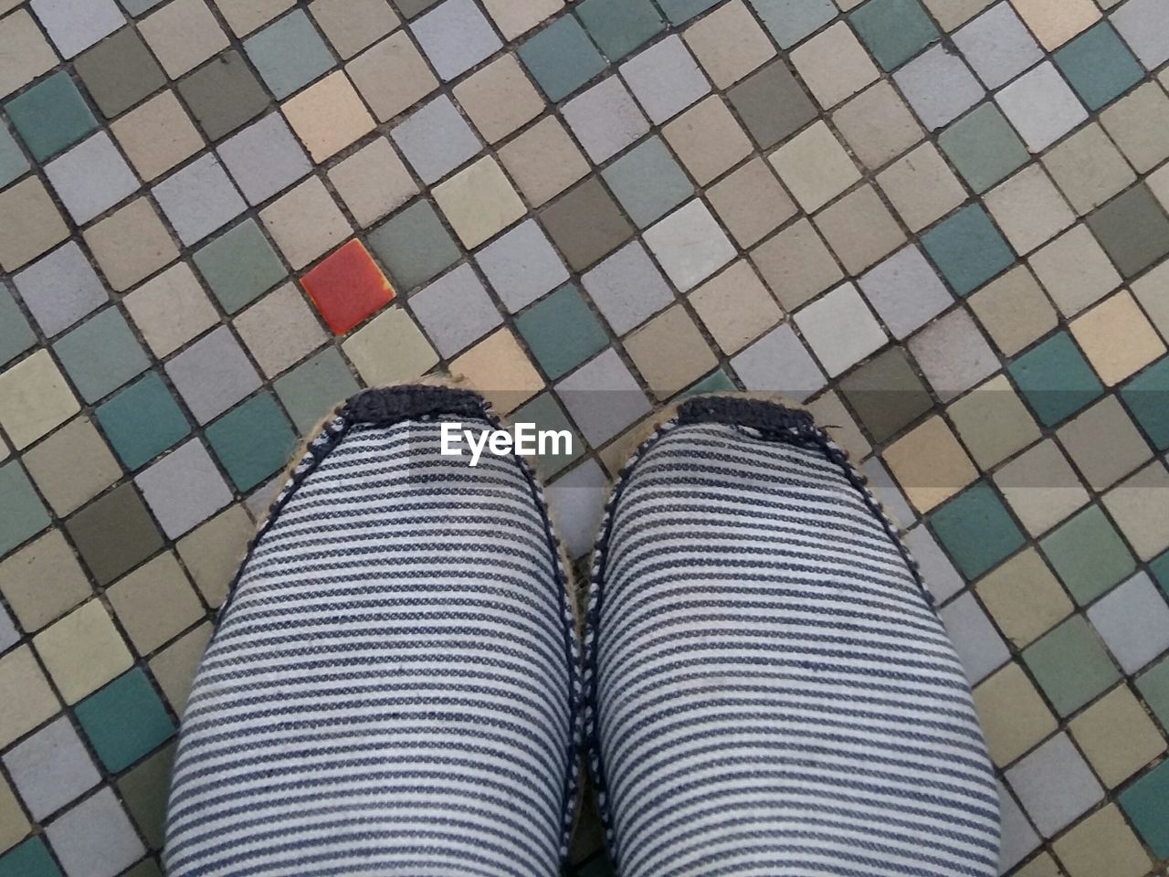 Midsection of woman wearing striped pants on tiled floor